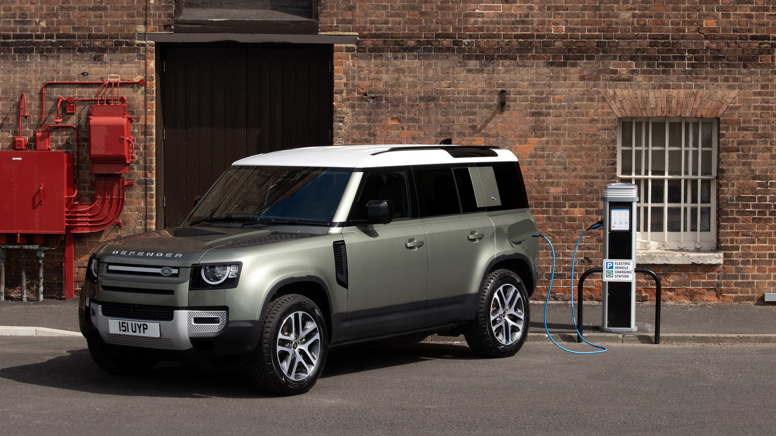 Parked defender near half brick wall building charging station PHEV