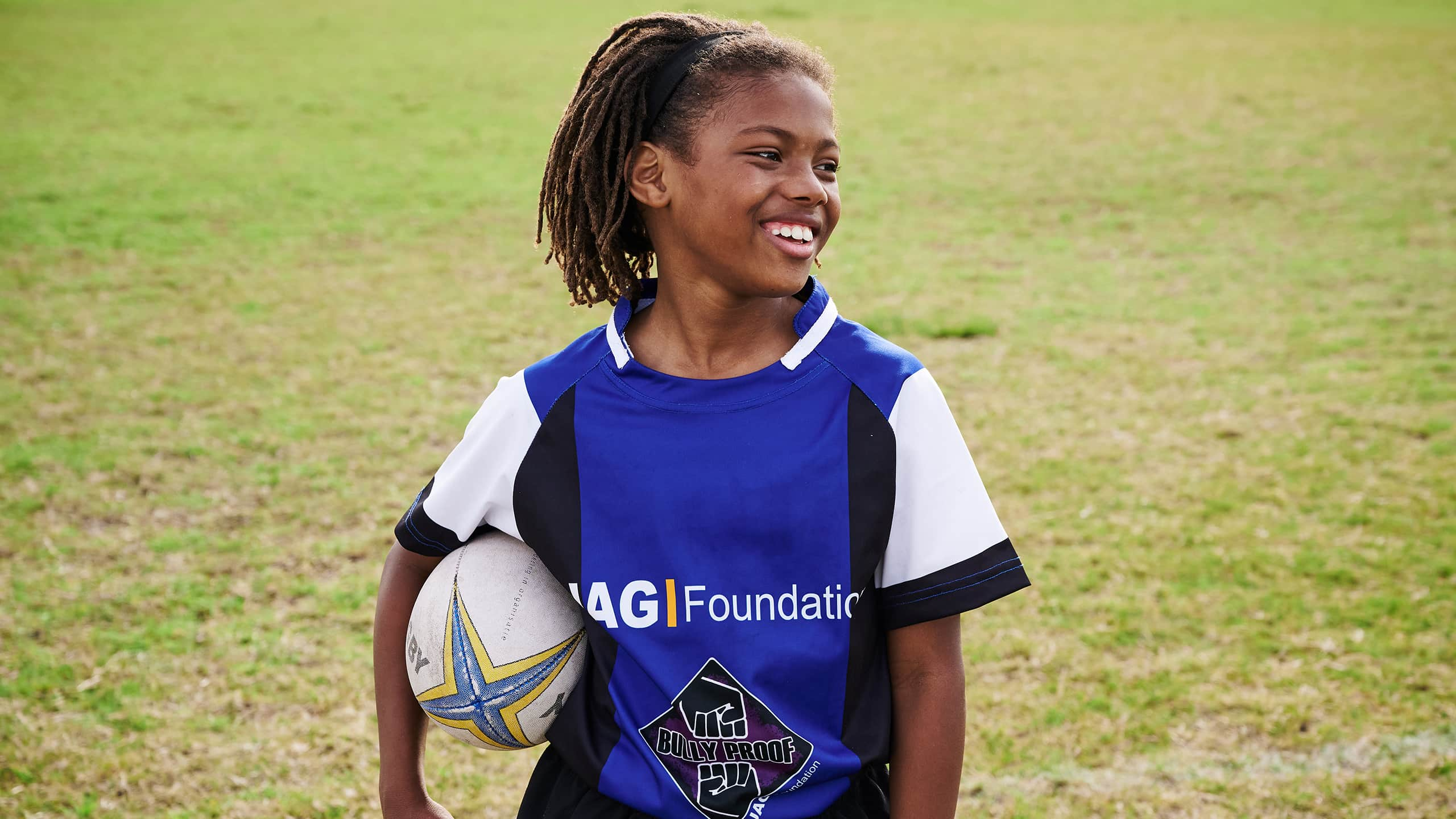 Happy girl playing rugby in the ground