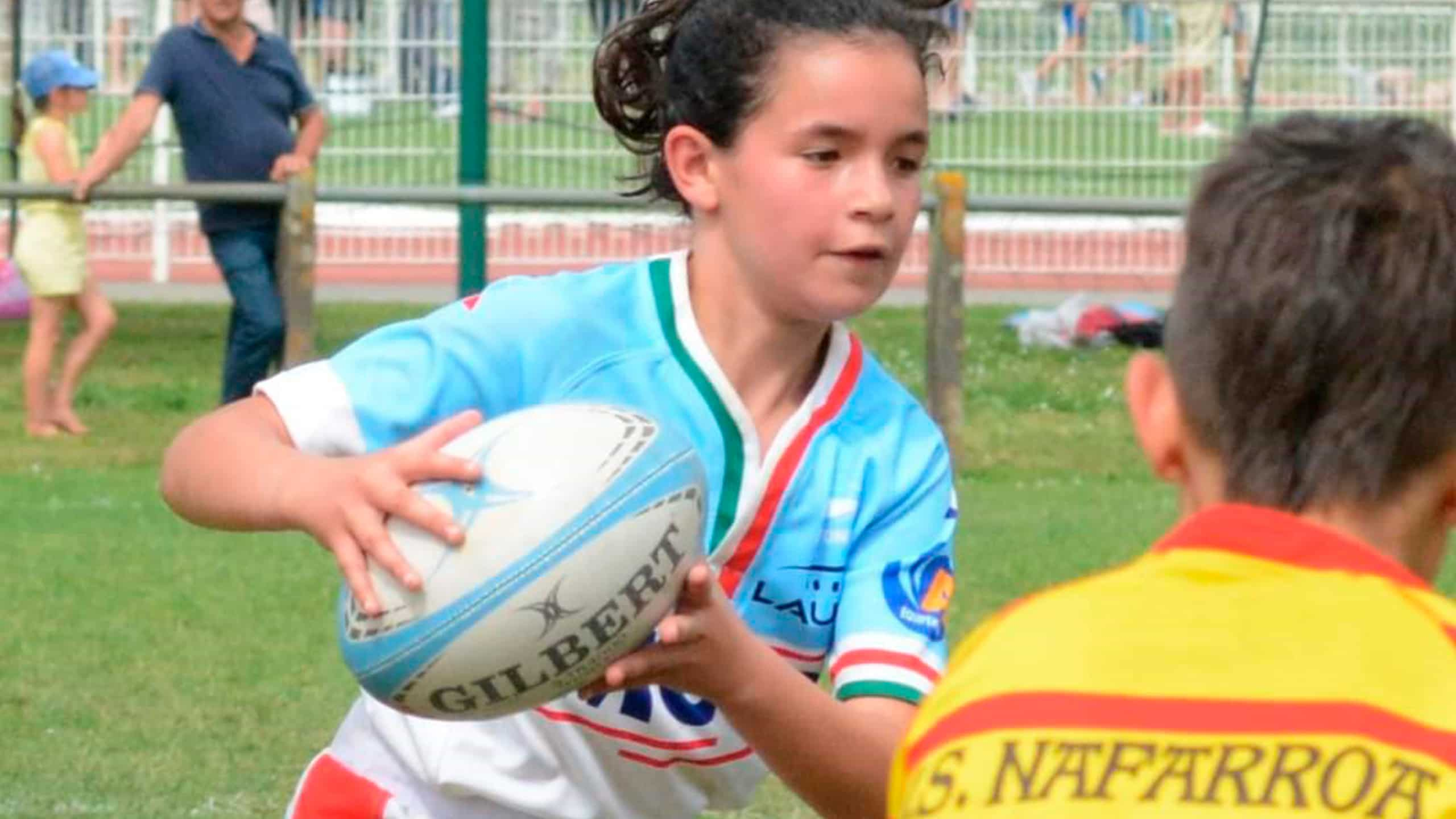 A girl playing Rugby in the ground