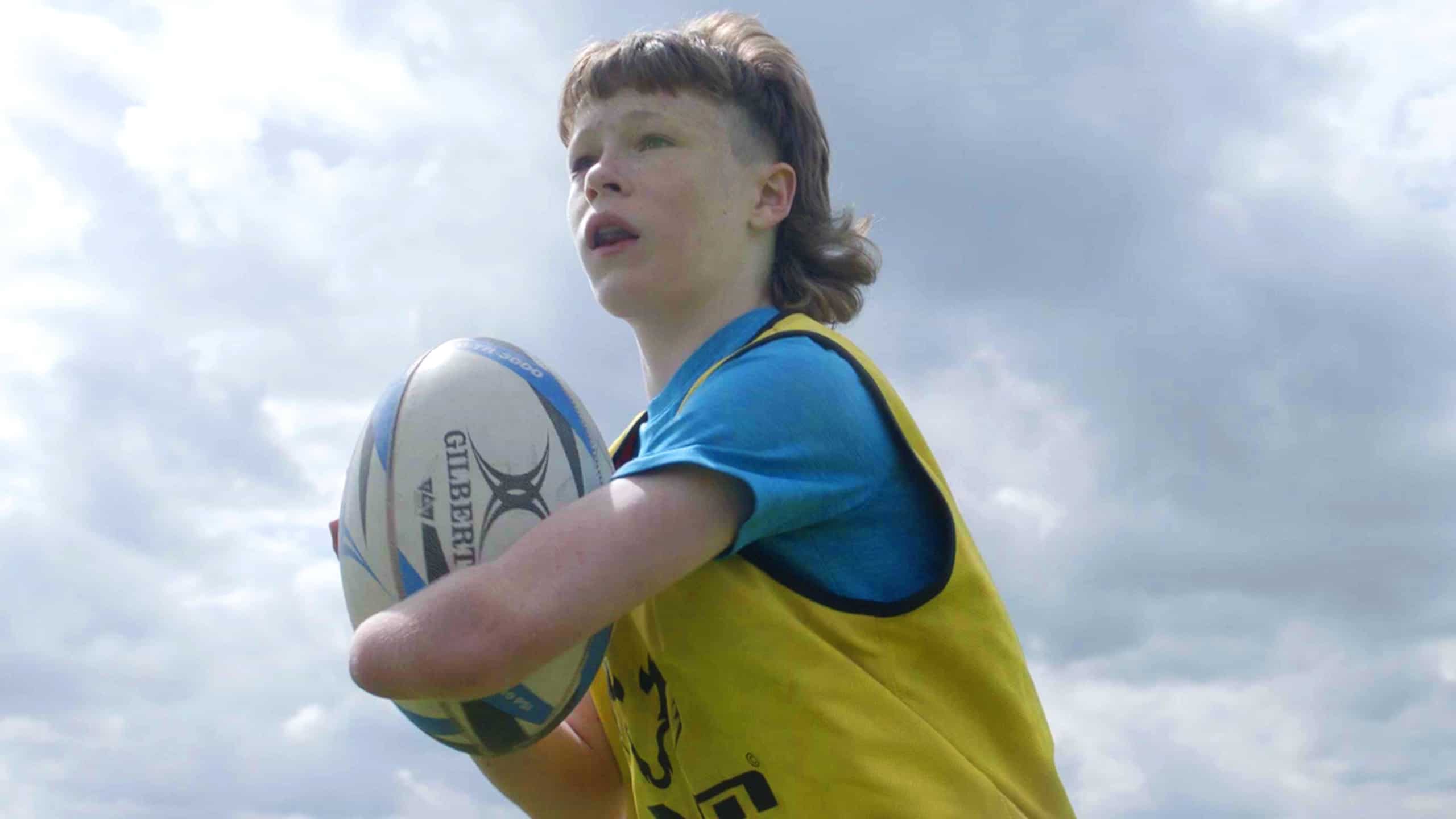 A girl playing Rugby in the ground