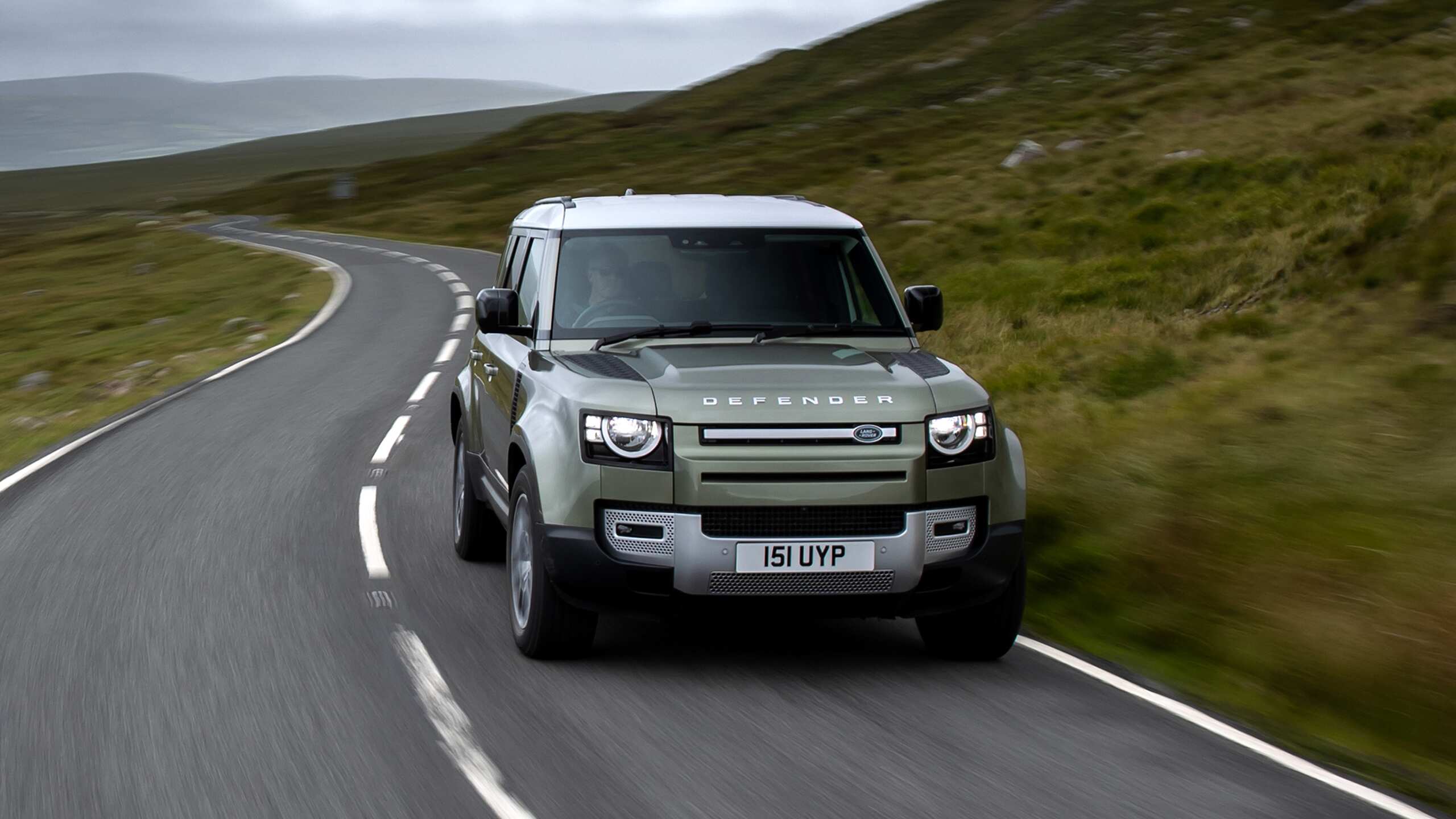 Defender running on the road among the mountains